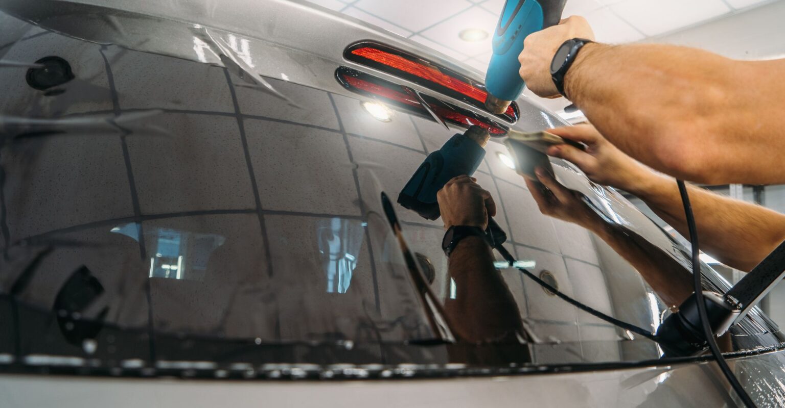 Heat-gun finishing a tint install on rear glass