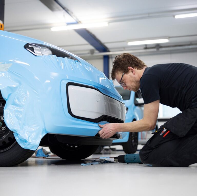 Installer applying paint protection film to a vehicle front